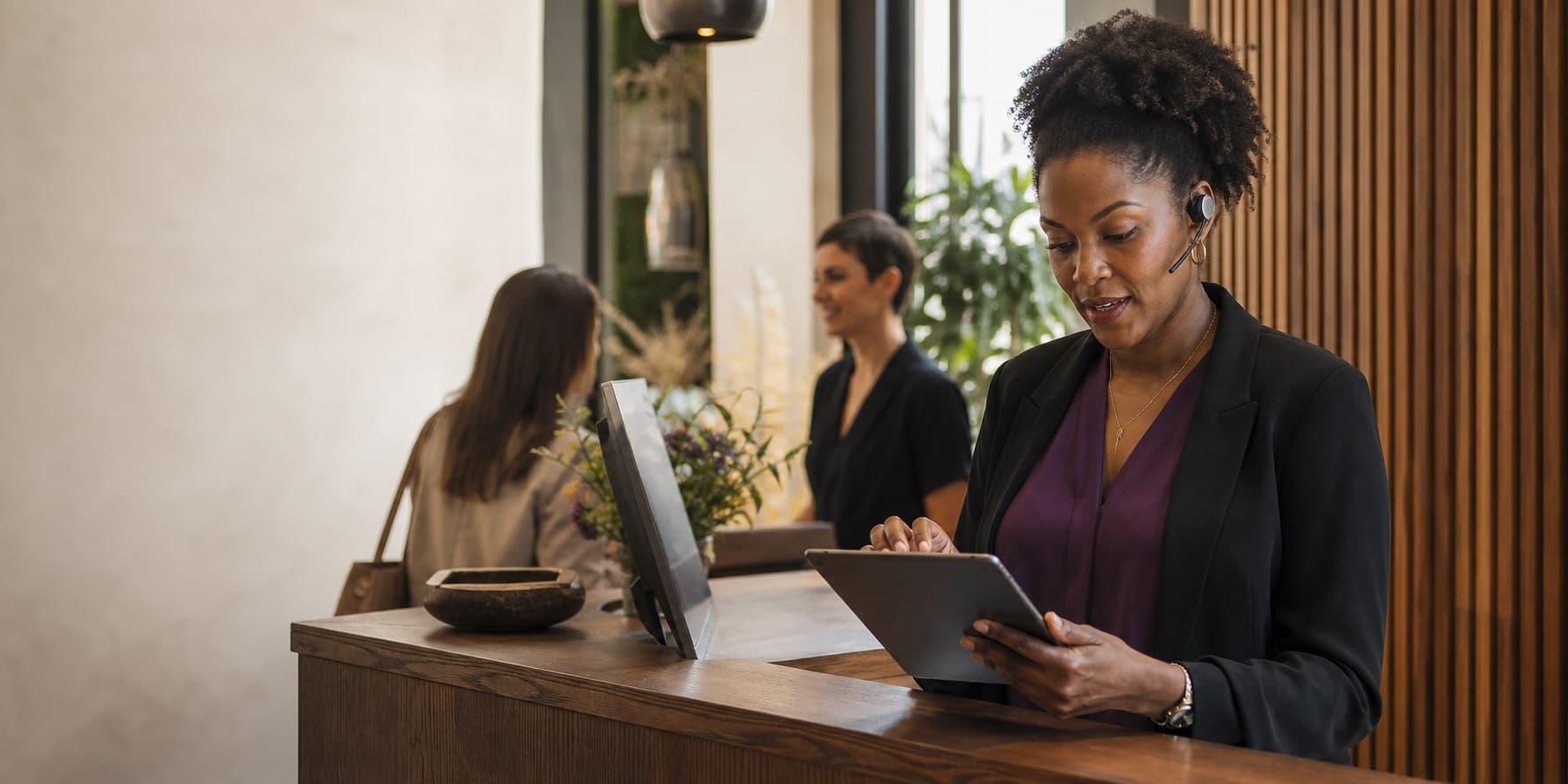 A service manager using a tablet while supporting customers at a reception desk